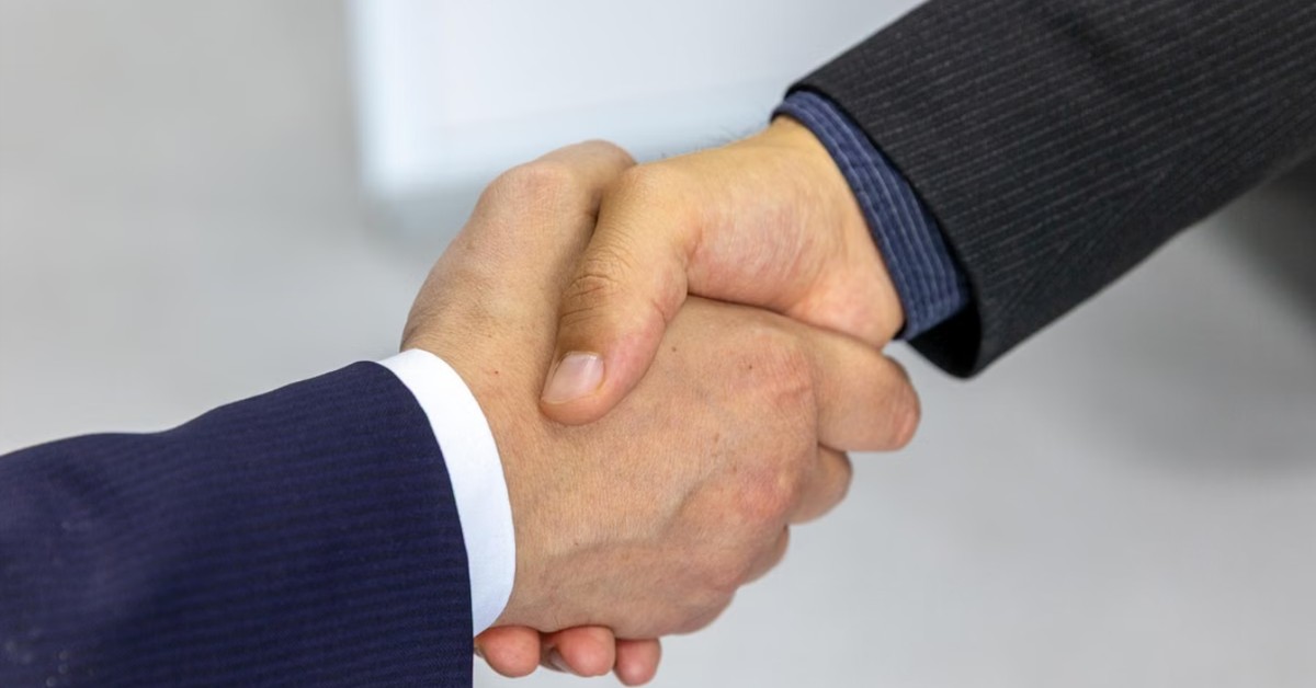 Two business professionals shaking hands, symbolizing an M&A deal closing under competitive pressure from a parallel Dual-Track IPO process
